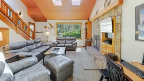 A spacious living room with a large sectional sofa, a fireplace, a television, and a stone fireplace surround. - BACK03 - Walk to Sunriver Village! Quiet Setting, 2 Suites, A/C, Hot Tub (Sunriver)
