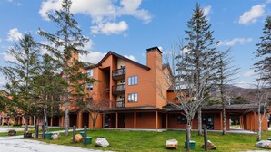 A multi-story hotel with a modern design, featuring balconies and large windows. - Charming 2-Bedroom Slopeside Condo at Pico Mountain E304 (Killington)