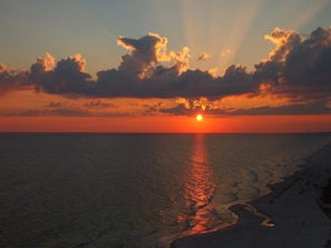 Un atardecer sobre una playa, con el sol reflejándose en el agua.