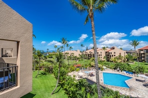 A resort with a swimming pool, palm trees, and a view of other buildings.