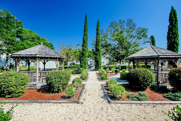 A garden with two gazebos, a gravel path, and neatly trimmed bushes. - Comfortable condo with two pools, sauna, hot tub, tennis - walk to the beach (Myrtle Beach)