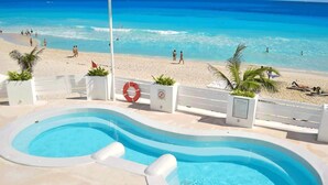 A swimming pool with a view of the beach and ocean. - Floor to Ceiling Glass Beachfront Cancun Penthouse! (Cancun)