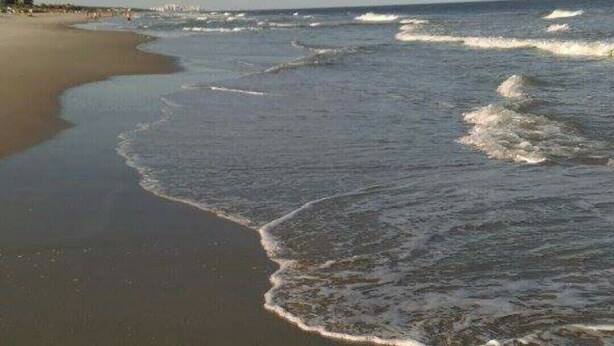 A beach with waves approaching the shore.