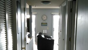 A hallway with a black couch, a clock on the wall, and doors leading to other rooms.