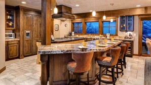A spacious kitchen with a large island, wooden cabinets, and bar stools.