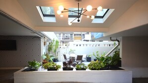 Un intérieur moderne agrémenté d’une verrière, d’un coin repas avec des chaises et de plantes en pot.