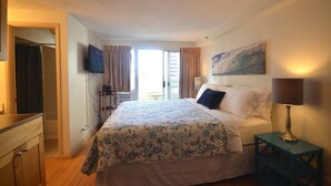 Une chambre d’hôtel avec un lit, une télévision, un tableau et une lampe.