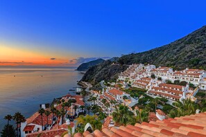 A coastal town with terracotta-roofed buildings, a clear view of the sea, and a hilly backdrop. - H412: Beautiful 2Bd Villa, 1462 SQ FT., Fireplace, Nice Ocean Views, Golf Cart (Avalon)