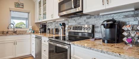 Enjoy cooking in this well-lit kitchen with a granite countertop, stainless steel appliances, and a dishwasher.