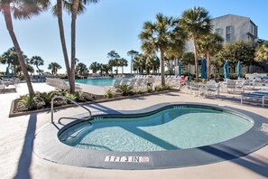A swimming pool with a 1 ft 3 in depth marker, surrounded by lounge chairs and palm trees.