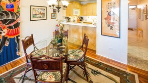 Un comedor con mesa de vidrio, sillas de madera y una lámpara de araña.