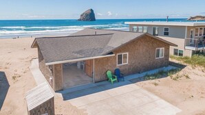 Ein Strandhaus mit überdachter Terrasse, zwei Stühlen und Blick auf das Meer.