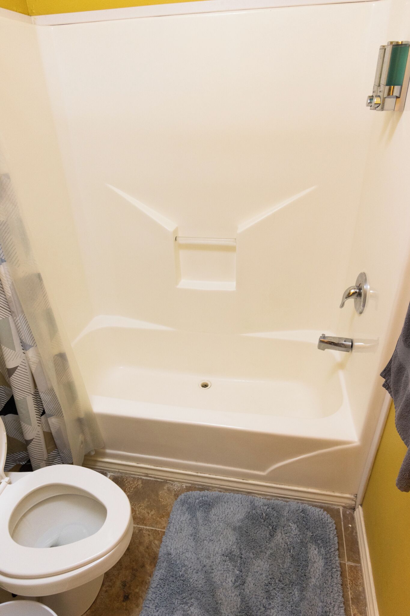Une salle de bain avec une baignoire, des toilettes et un tapis bleu.