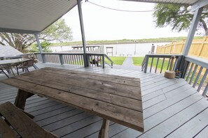 A wooden deck with a table and benches, overlooking a body of water.