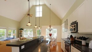 A spacious kitchen with a large island, white cabinetry, and a dining area with a view of the outdoors.