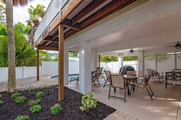 An outdoor patio area with a pool, seating, and a covered section.