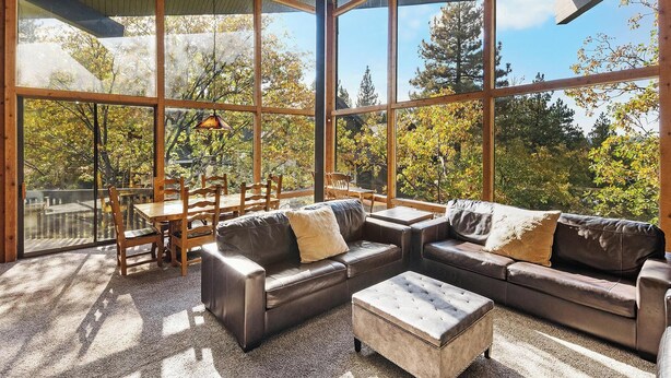 Una habitación amplia con ventanas grandes, una mesa de comedor de madera y un juego de sofá de cuero.