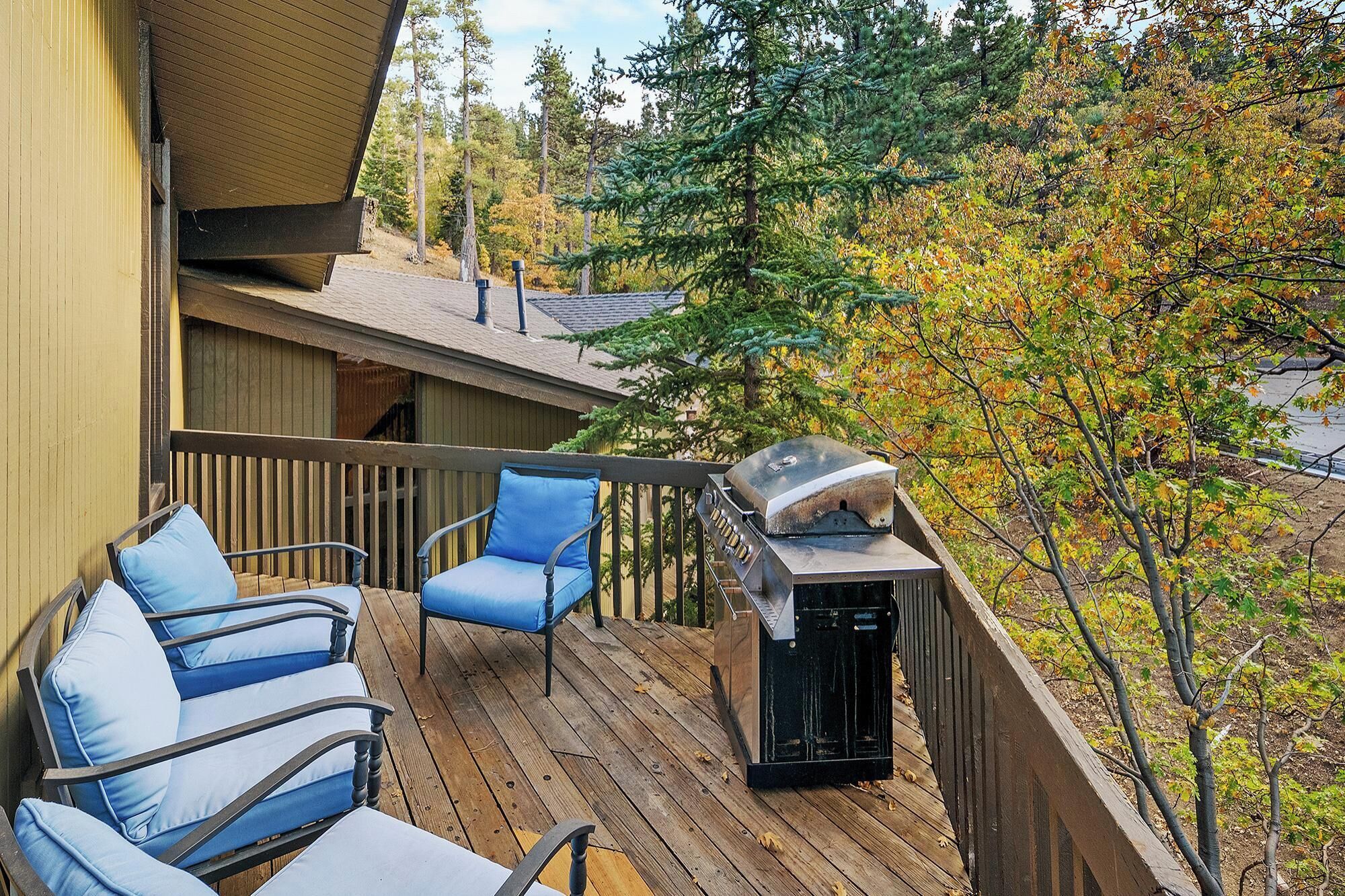 A wooden deck with outdoor seating and a barbecue grill.