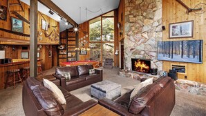 Un interior acogedor con chimenea de piedra, sofás de cuero, mesa de billar y zona de bar.