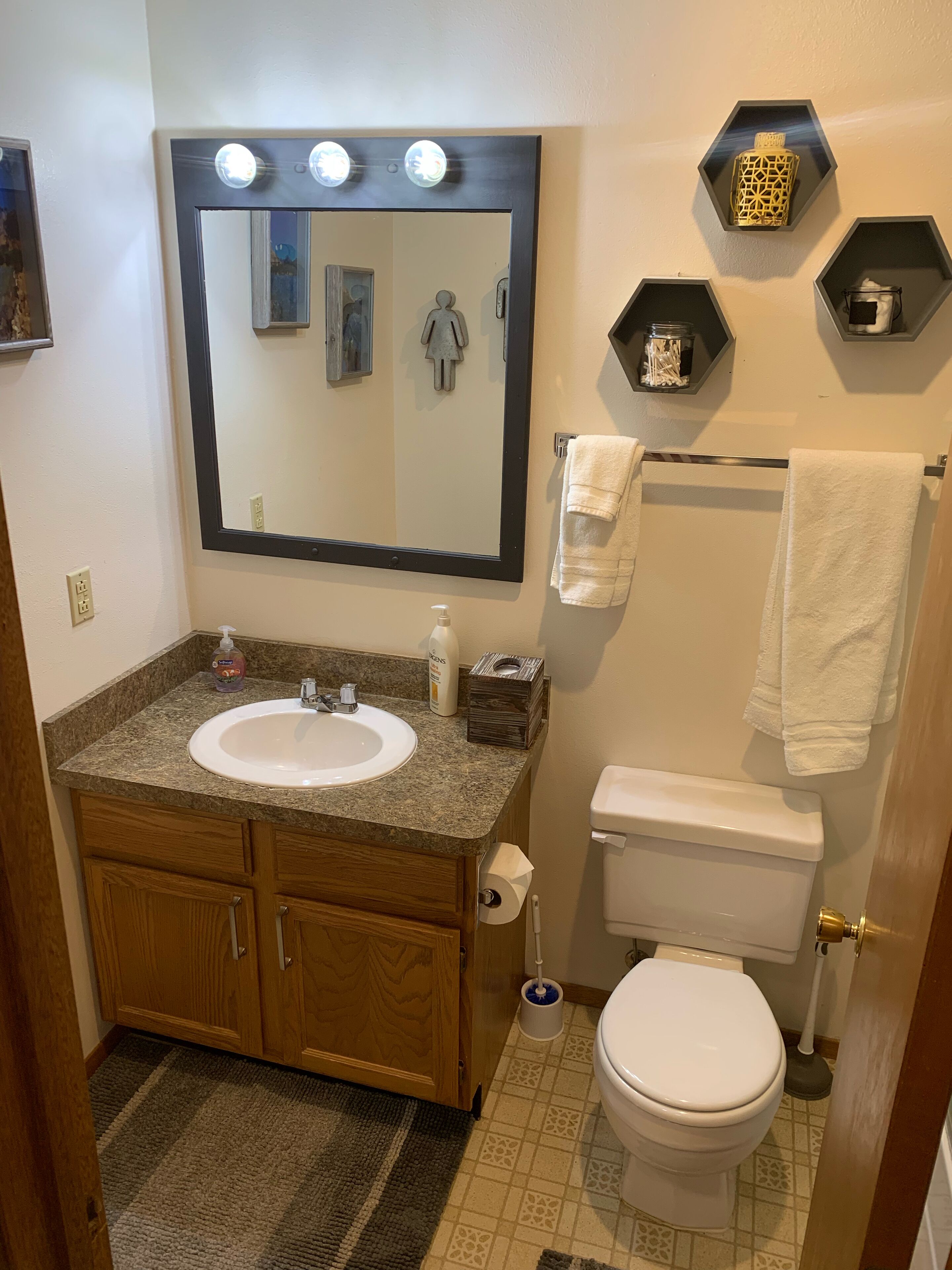 Une salle de bain équipée d’un lavabo, d’un miroir, d’un meuble-lavabo, de toilettes et d’un porte-serviettes.