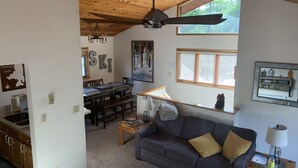 A cozy living room with a wooden ceiling, a dining area with a table and chairs, and a kitchen with cabinets and a sink. - 2 story 3 bedroom Ski condo on Hailey’s run at Whitefish Mountain Resort.  (Whitefish)