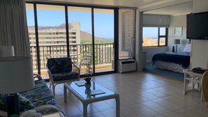 Habitación de hotel con balcón, cama, televisión y vista a la ciudad.