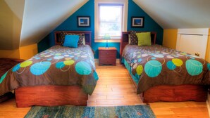 A bedroom with two beds, a window, and a nightstand.