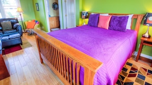 A bedroom with a large bed, a wooden headboard, a sofa, and a lamp.