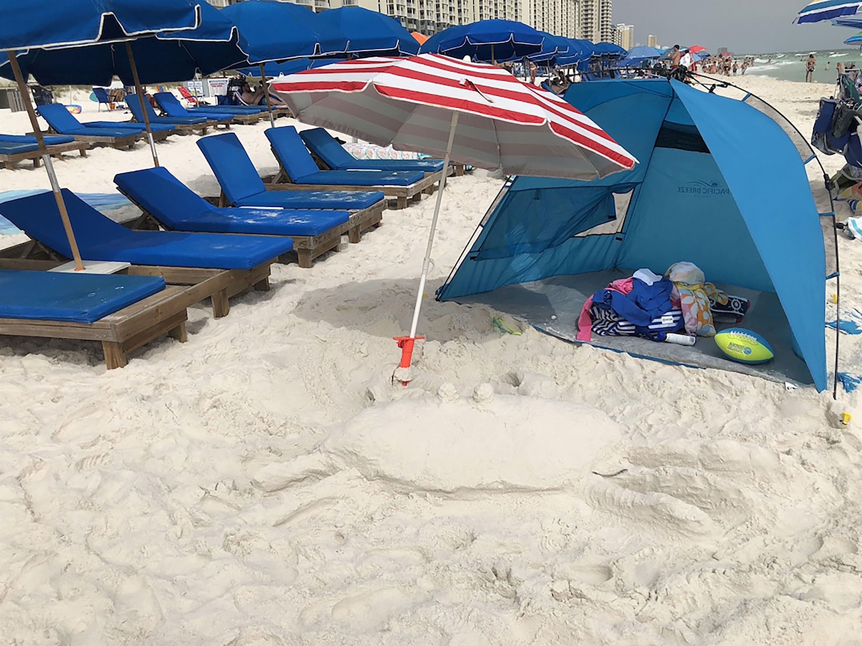 Een strand met blauwe ligbedden en een tent met een Amerikaanse vlag.