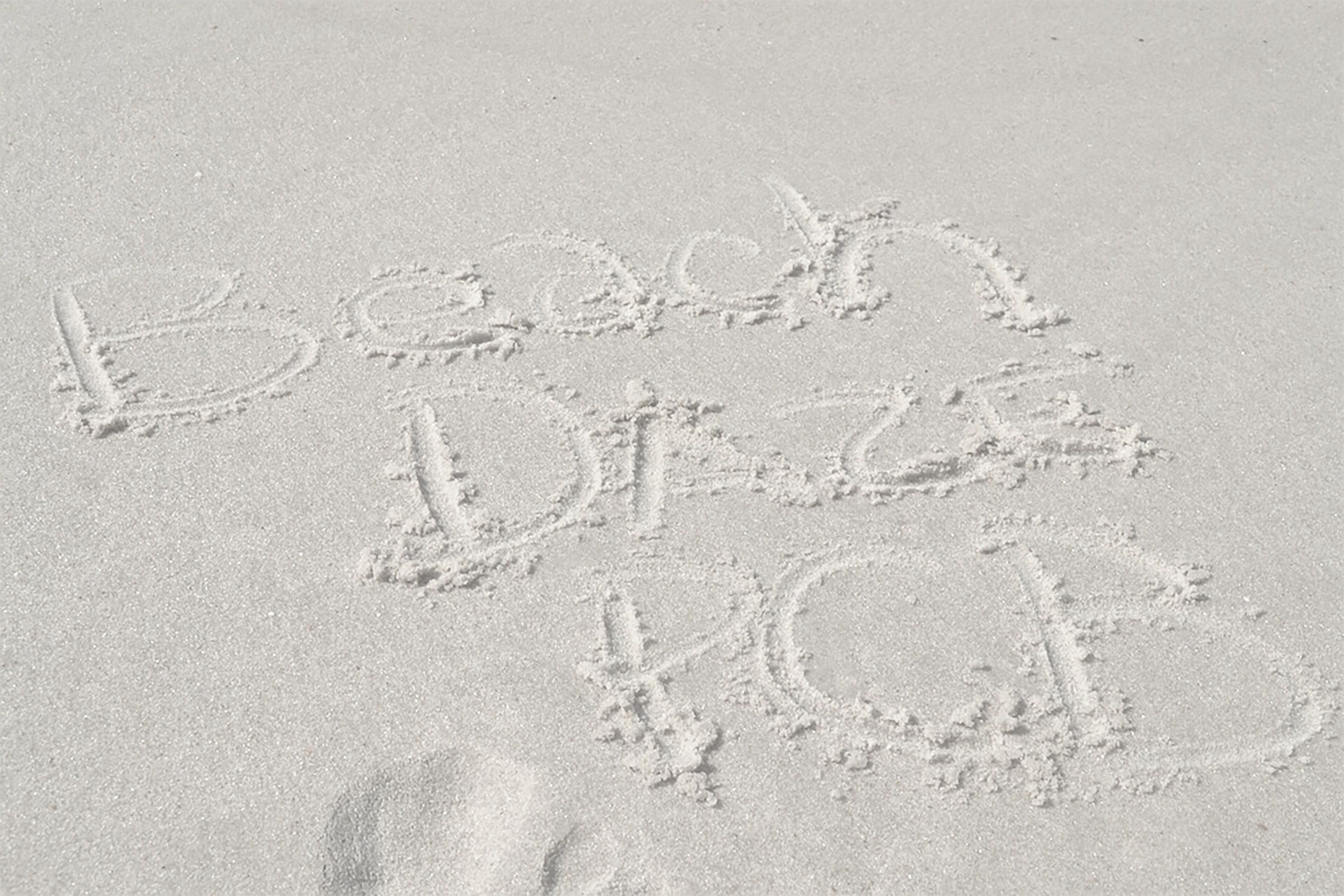 Des empreintes de pas dans le sable forment les mots « Beach Dance Party ».