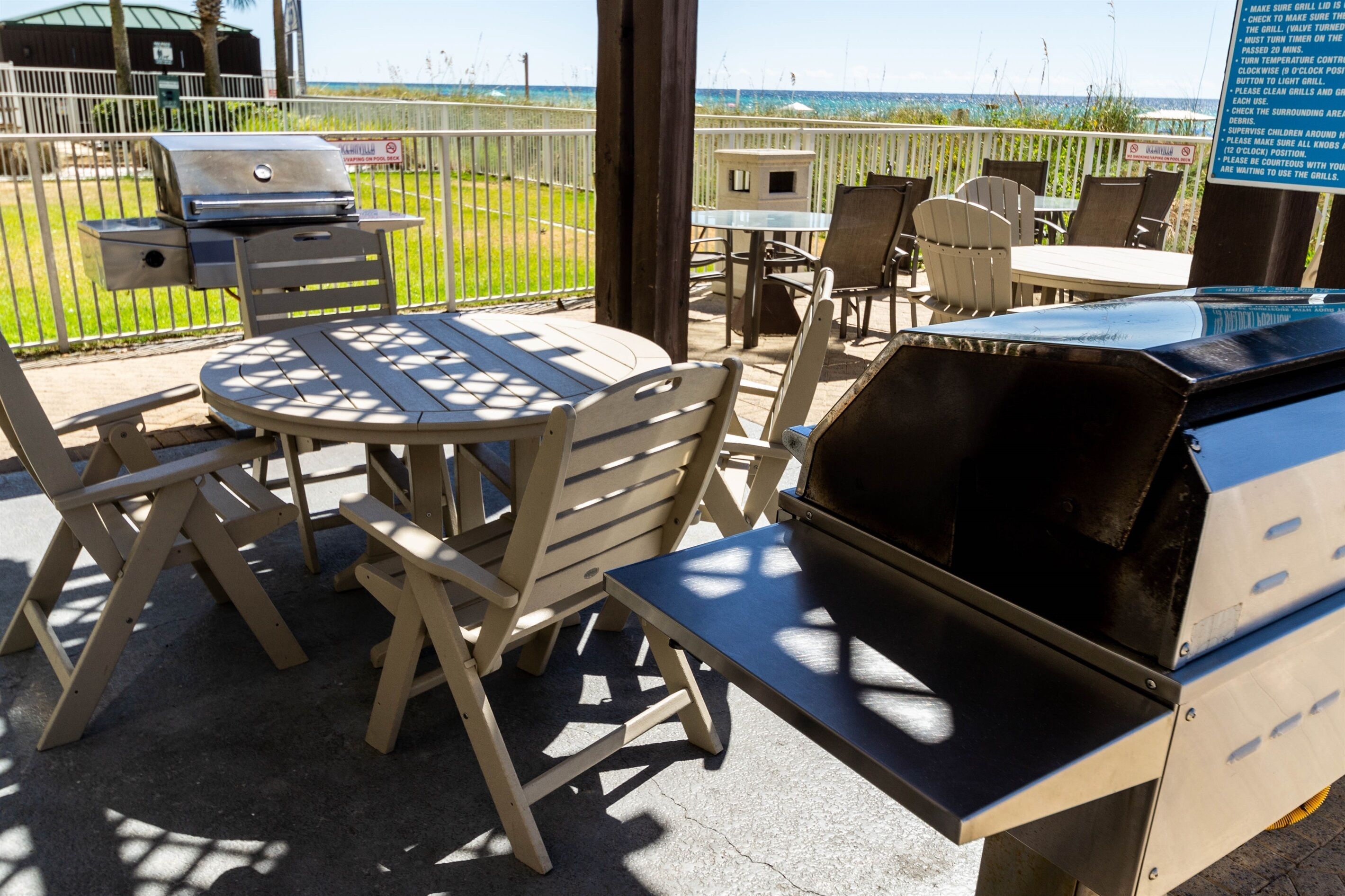 Une terrasse extérieure avec un barbecue, des sièges et une vue sur la plage.