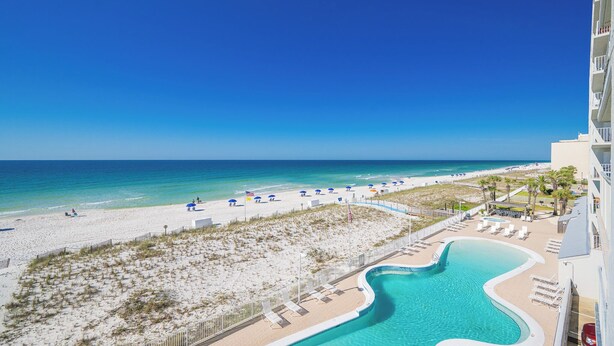 A resort with a beach, a pool, and a view of the ocean.