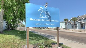 A sign for Mustang Isle Condominiums located at 2025 S. 11th Street. - This is the perfect cozy island bungalow for a weekend of fishing or just hangin (Port Aransas)