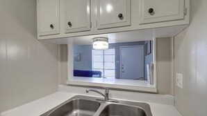 A kitchen with two stainless steel sinks, white cabinets, and a mirror above the sink. - This is the perfect cozy island bungalow for a weekend of fishing or just hangin (Port Aransas)