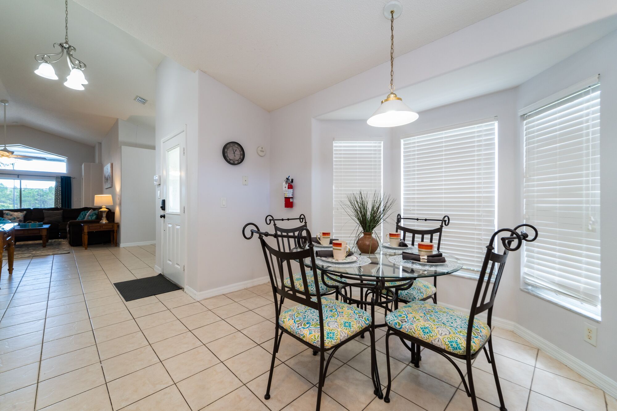 A dining area with a round glass table, black metal chairs, and a potted plant.