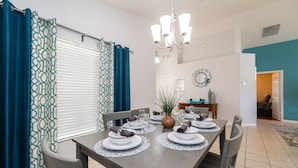 Un comedor con una mesa dispuesta para cuatro, un candelabro y vista a otra habitación.