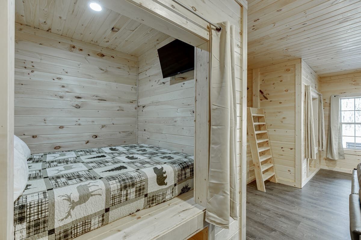 Eine Holzhütte mit einem Bett, einem Fernseher und einem Fenster.