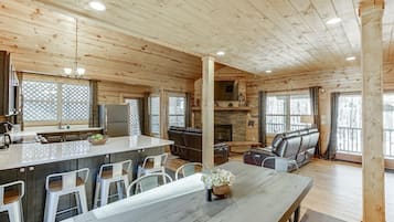Interior de una cabaña de madera con cocina, comedor y zona de estar.