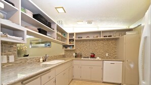 Eine moderne Küche mit weißen Schränken, einer Granit-Arbeitsplatte und einer eingebauten Backspüle aus Ziegelsteinen.