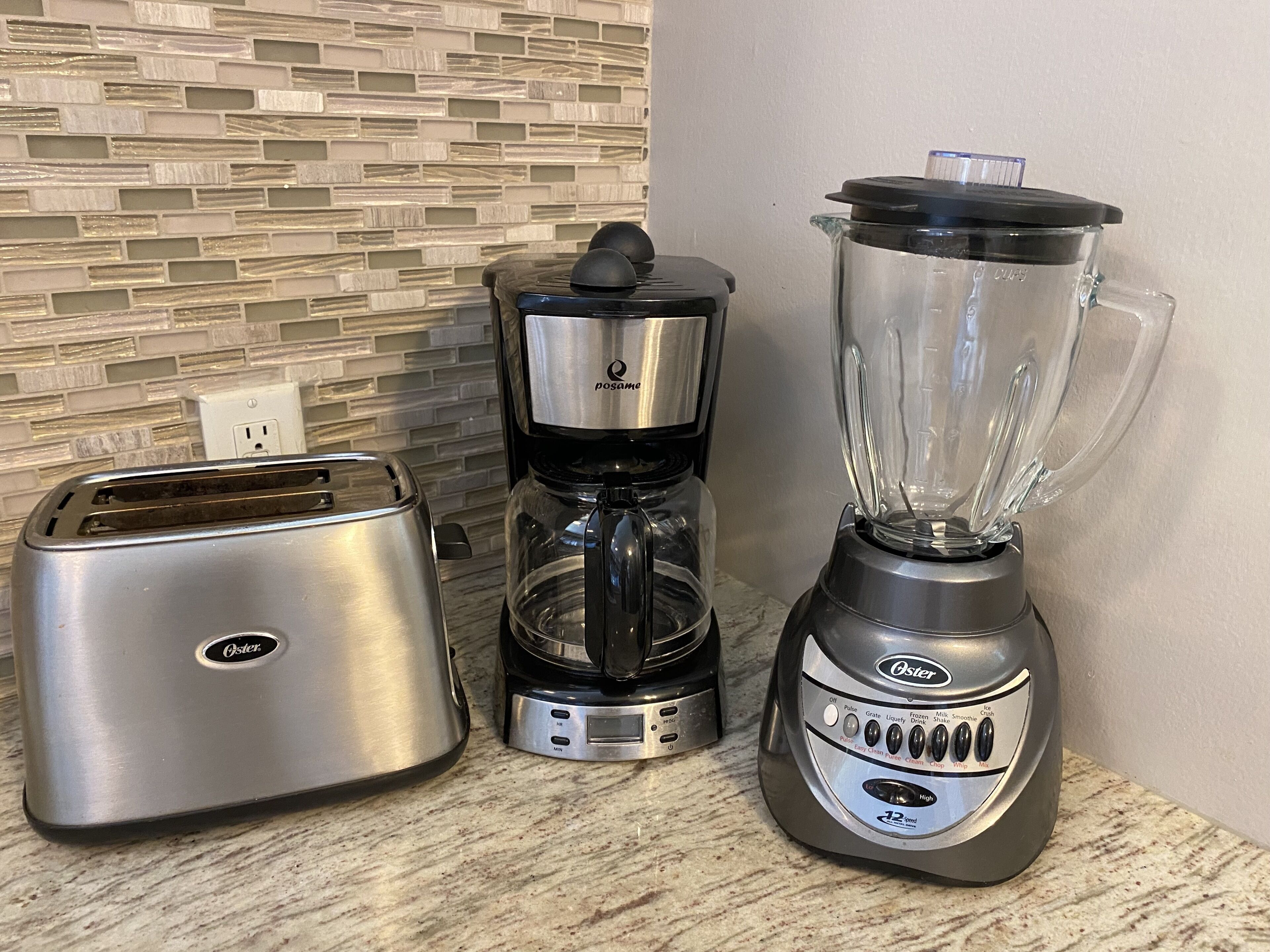 A kitchen with a toaster, a coffee maker, and a blender on a countertop.