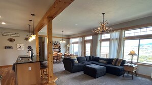 Amplia sala de estar con un sofá seccional grande, una mesa de comedor de madera y una zona de cocina con barra.