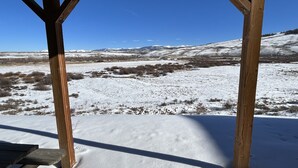 Una estructura de madera con vistas a un paisaje nevado y montañas distantes.