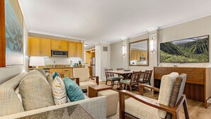Un espacio habitable compacto con kitchenette, comedor y una pantalla de televisión grande.