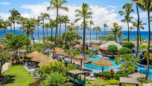 Un resort con piscina, sillas de descanso y sombrillas.