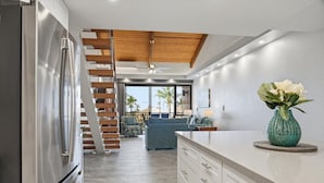 Una cocina moderna con un refrigerador de acero inoxidable, una escalera de madera y un comedor con vistas.