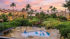 Un resort con piscina, sillones de descanso y palmeras.