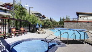Une piscine avec un jacuzzi, des chaises longues et un espace salon couvert.