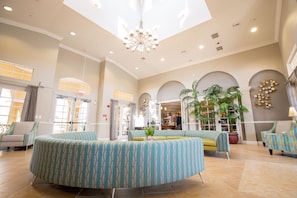 Relax in the hotel's spacious lobby, featuring a seating area with a round sofa and armchairs, surrounded by lush greenery and natural light.
