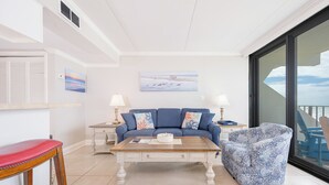 A living room with a blue sofa, a wooden coffee table, a red chair, and a patterned armchair.