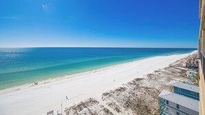 Une vue sur la plage, avec un ciel dégagé, une plage de sable et des bâtiments le long du rivage.